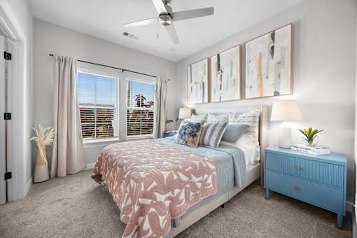 A bedroom with a bed, nightstand, and a ceiling fan.