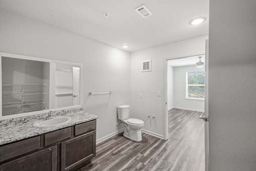 A bathroom with a toilet, sink, and mirror.