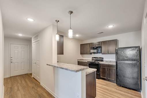 A kitchen with a marble countertop and a black refrigerator.