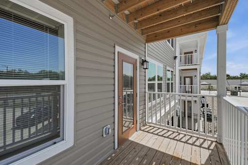 A deck with a white railing and a brown door.