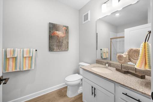 A bathroom with a toilet, a sink, and a painting of a flamingo.