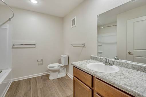 A bathroom with a toilet, sink, and mirror.