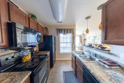 A kitchen with black appliances and wooden cabinets.