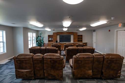 A room with brown leather chairs and a television.