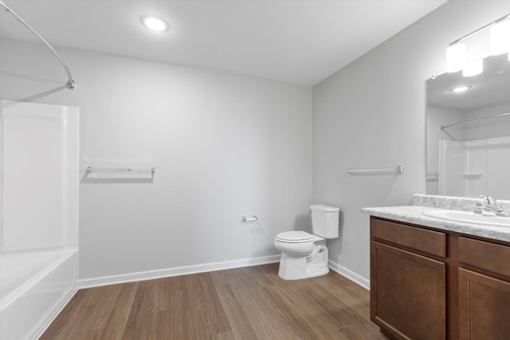 A white bathroom with a toilet, sink, and mirror.