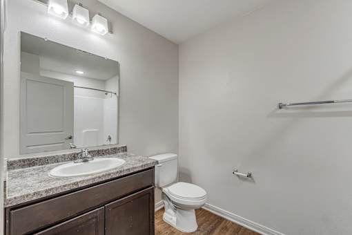 A white toilet sits in a bathroom next to a sink and mirror.