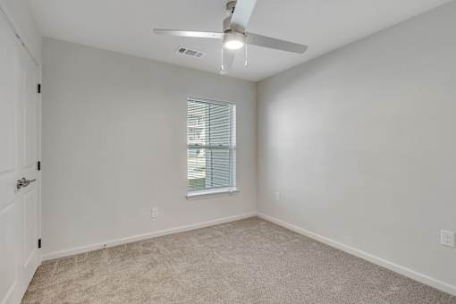 A room with a ceiling fan and carpeted floor.