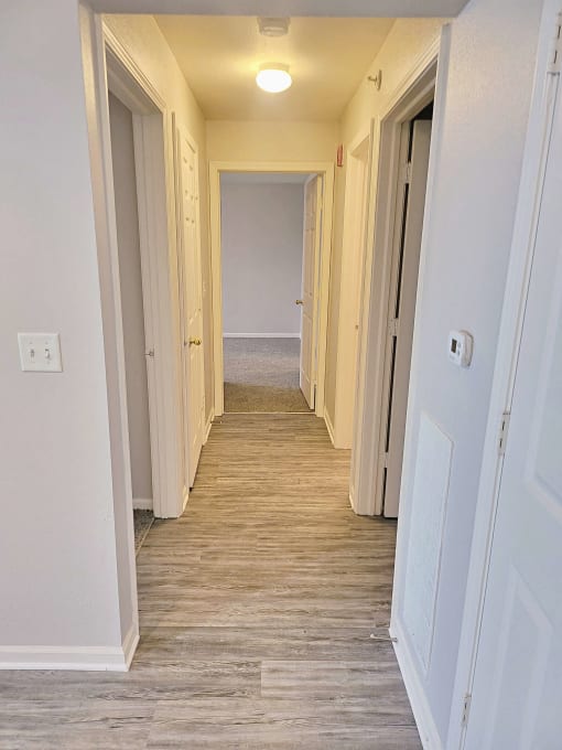 an empty hallway with a wood floor and white walls and doors