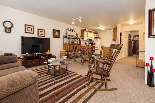 A living room with a brown couch and a wooden rocking chair.