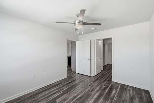 A room with a ceiling fan and wood flooring.