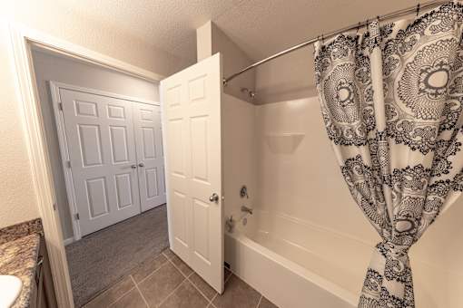 A bathroom with a bathtub, shower curtain, and two doors.