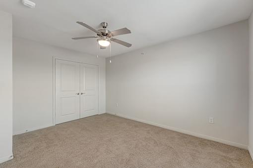 A room with a ceiling fan and carpeted floor.