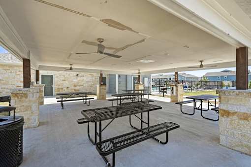A patio with tables and chairs and a ceiling fan.
