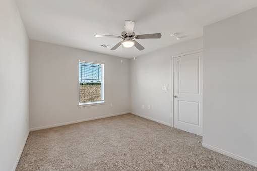 A room with a ceiling fan and a window with blinds.