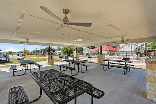 A patio with tables and chairs under a roof.