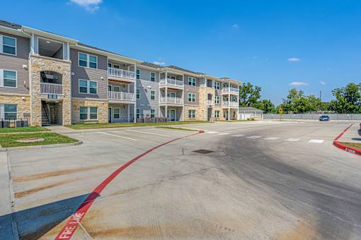 A parking lot in front of a multi-story apartment building.
