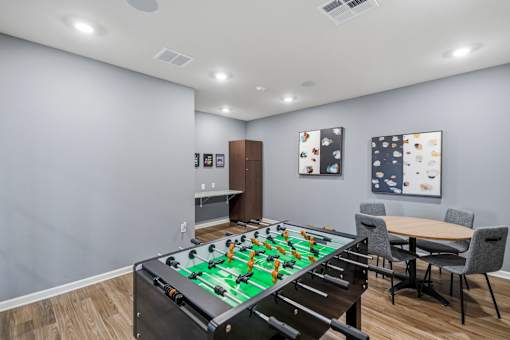 A foosball table is in the middle of a room with a dining table and chairs.