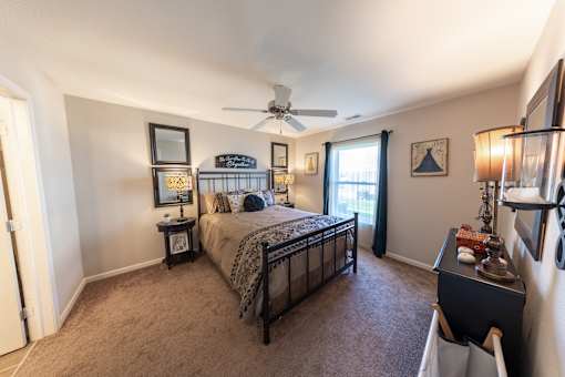 A bedroom with a bed, nightstand, and a ceiling fan.