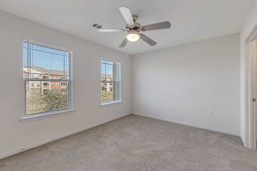 A room with a ceiling fan and carpeted floor.