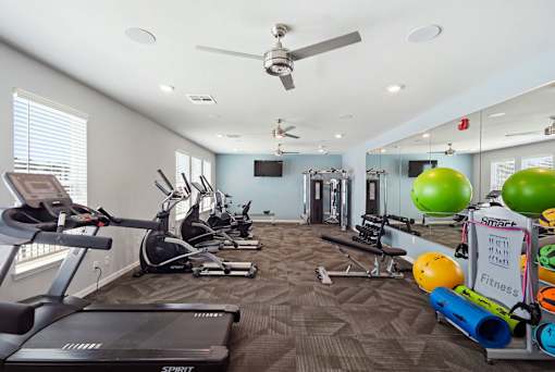 A fitness room with a treadmill, exercise balls, and other equipment.