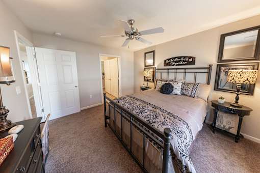 A bedroom with a large bed and a ceiling fan.
