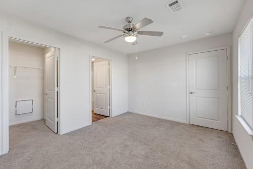 A room with a ceiling fan and carpeted floor.