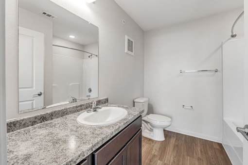 A bathroom with a sink, toilet, and mirror.