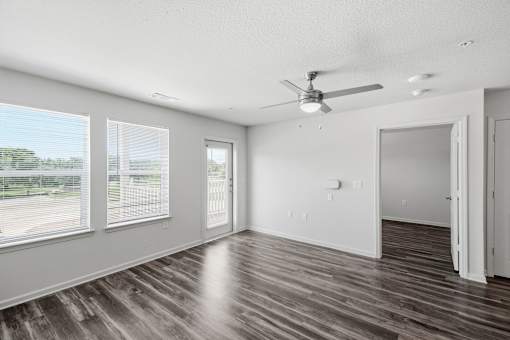 A room with a ceiling fan and sliding glass doors.