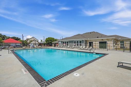 A large outdoor swimming pool with a red roofed building in the background.