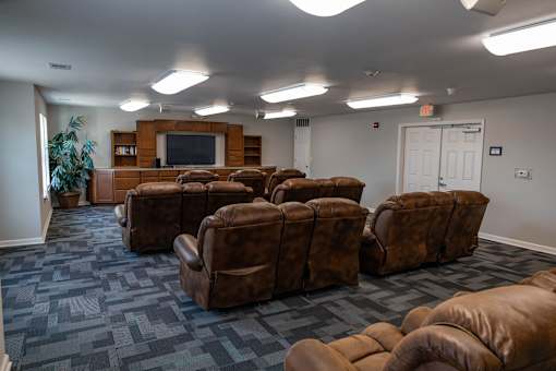 A room with brown leather chairs and a television.