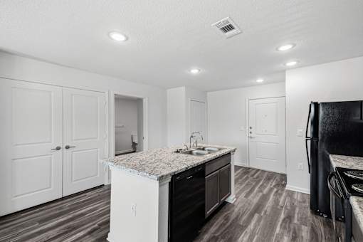 A kitchen with a granite countertop and dark wood flooring.