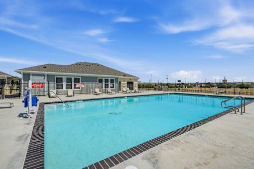 A large outdoor swimming pool with a building in the background.