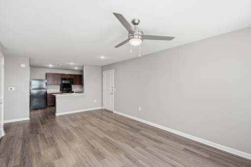 A room with a ceiling fan and wooden flooring.