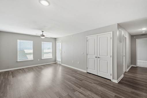A room with a ceiling fan and wooden flooring.