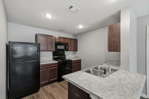 A kitchen with a black refrigerator, microwave, and stove.