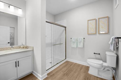 A white bathroom with a toilet, sink, and shower.