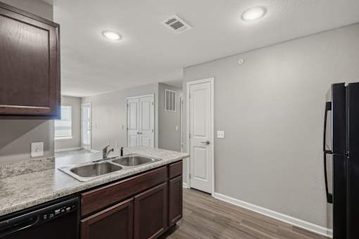 A kitchen with a black fridge and brown cabinets.