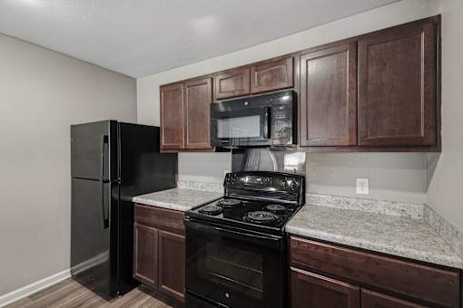 A black refrigerator and stove in a kitchen with brown cabinets.