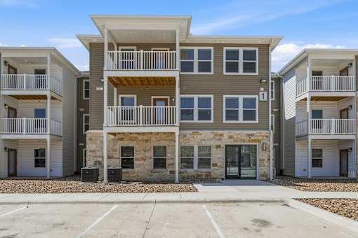 A row of modern townhouses with balconies and a mix of stone and siding exteriors.