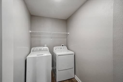 Two white front loading washing machines in a small laundry room.