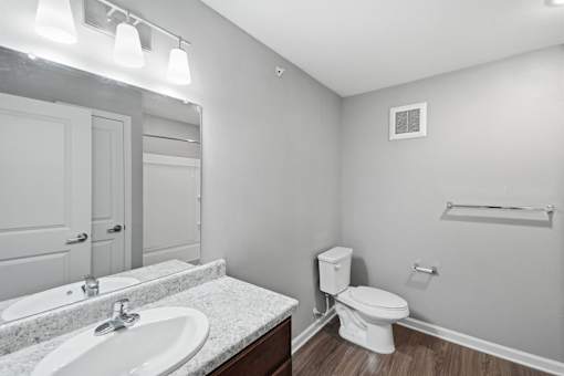 A white toilet sits in a bathroom with a marble countertop and a white sink.