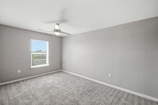 A room with a carpeted floor and a window.