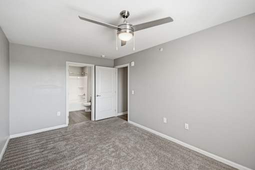 A room with a ceiling fan and carpeted floor.