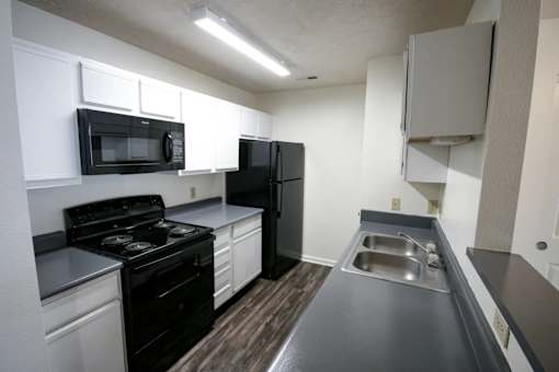 A kitchen with black appliances and white cabinets.