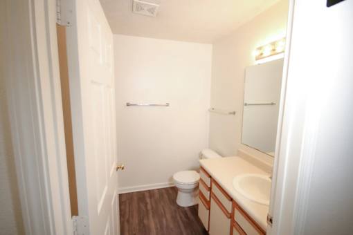 A white bathroom with a toilet, sink and mirror.