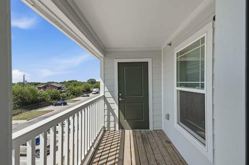 A balcony with a green door and a window.