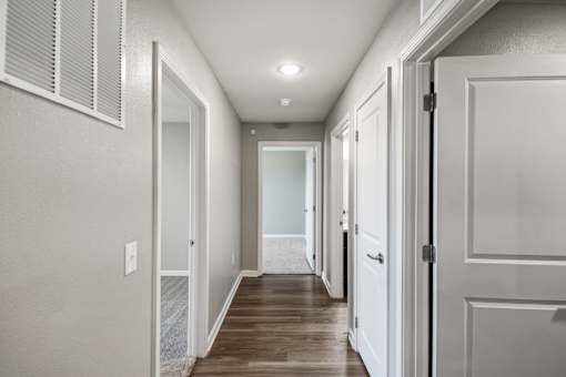 A long hallway with white doors and a light on the ceiling.