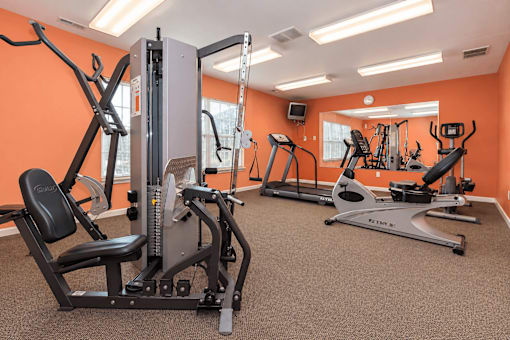 A gym with orange walls and a variety of exercise equipment.