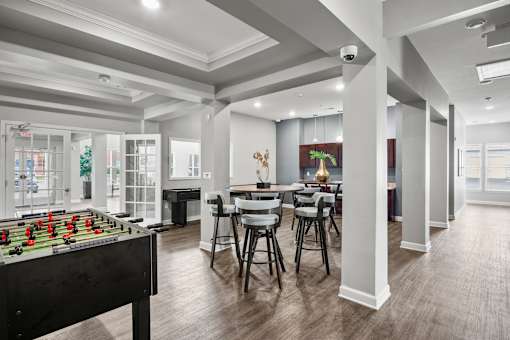 A foosball table is in the middle of a room with a dining table and chairs.