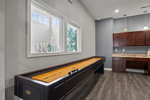 A pool table is in the middle of a room with a window and a sink.